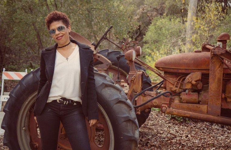 Model standing in front of a vintage tractor wearing raybans