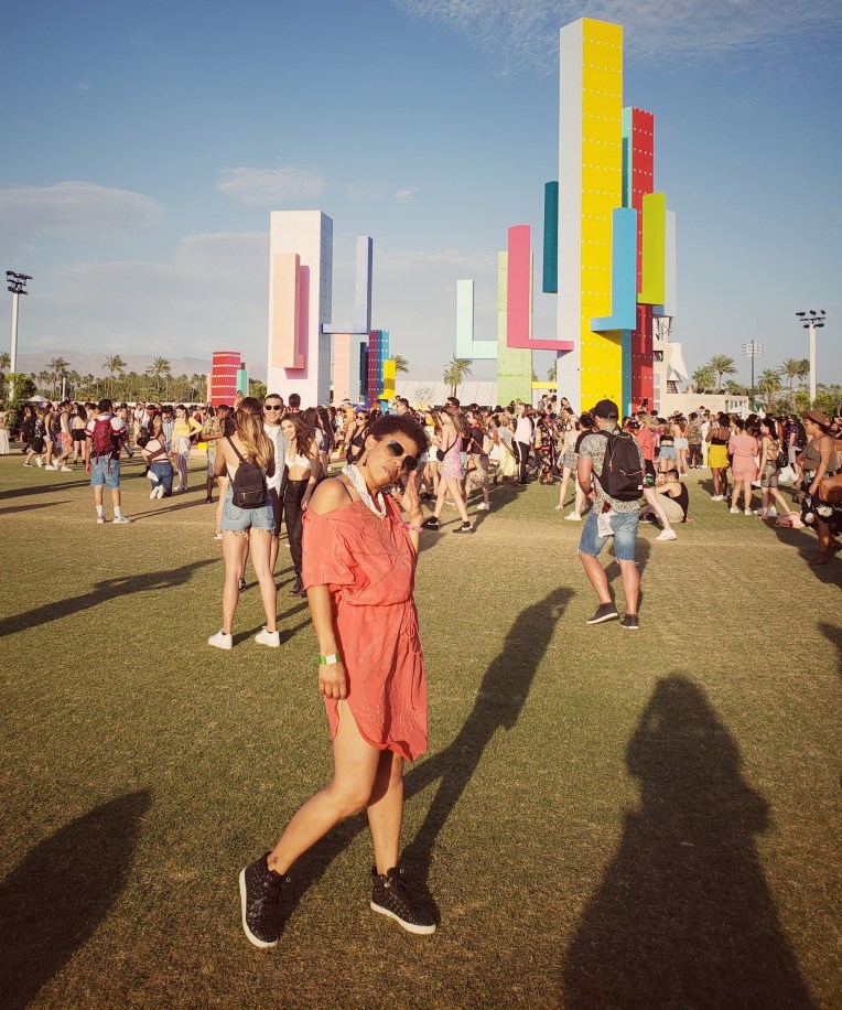 Girl in an orange dress and black sneakers in front of art installation at Coachella festival