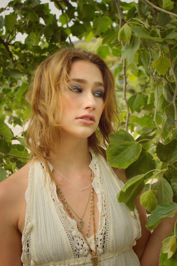 Portrait of a young women standing underneath a tree surrounded by leaves 
