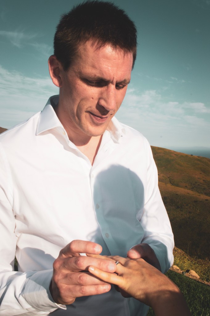 Groom placing wedding band on the brides finger