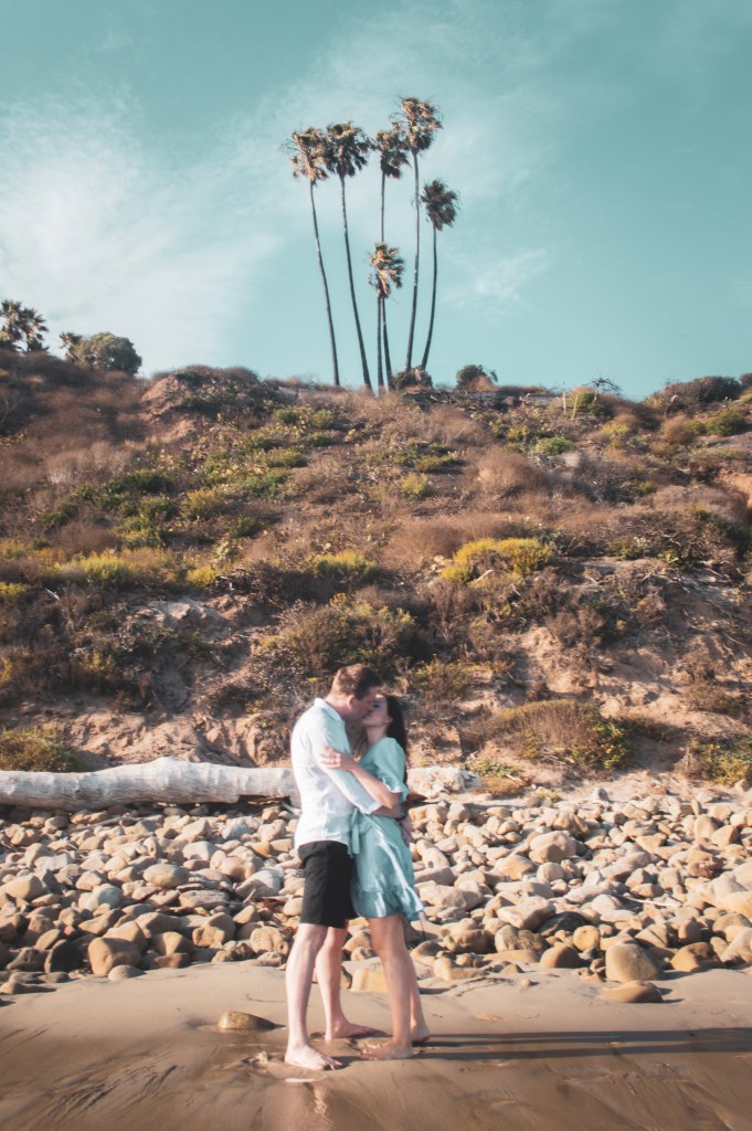 Couple kissing on the beach with palm trees
