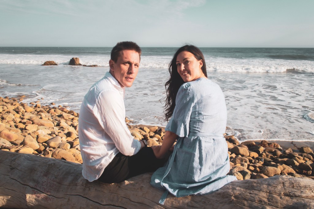 Couple sitting on a log looking back on the beach