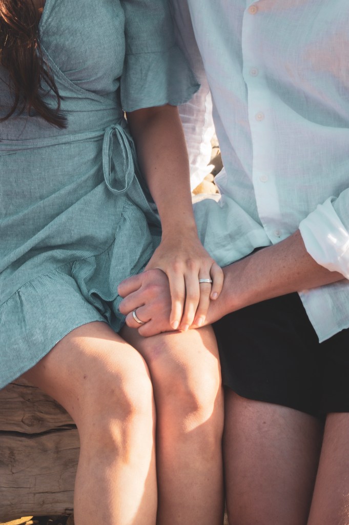Couples hands on woman’s lap with wedding bands
