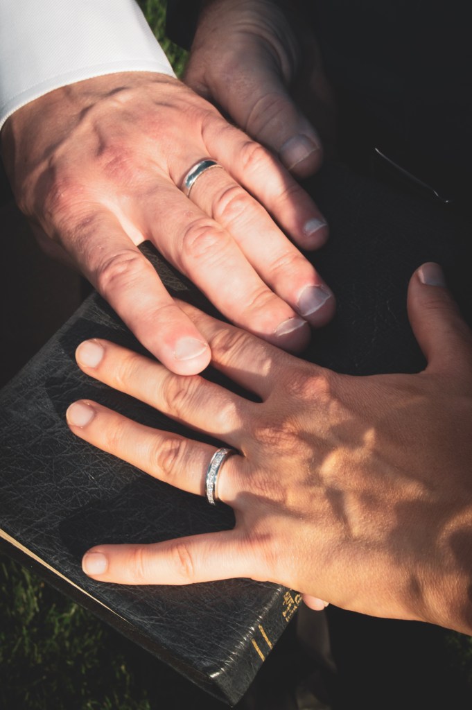 Hands with wedding rings placed on a bible