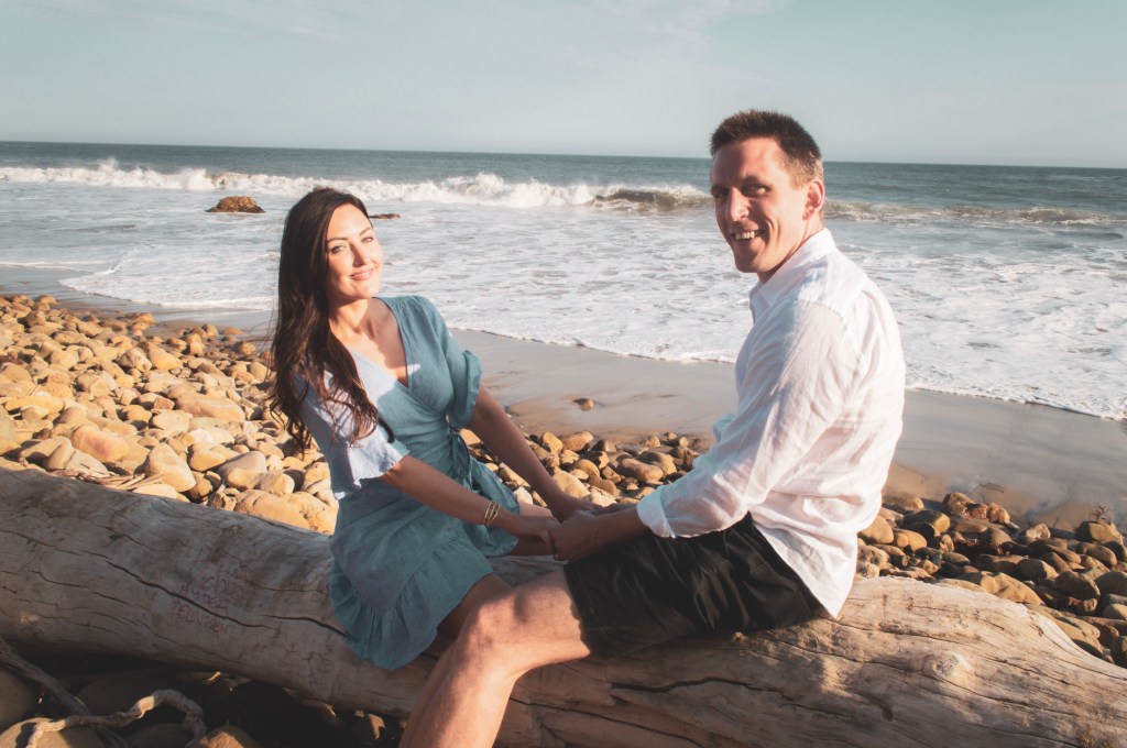 Couple sitting on a log in front of the beach