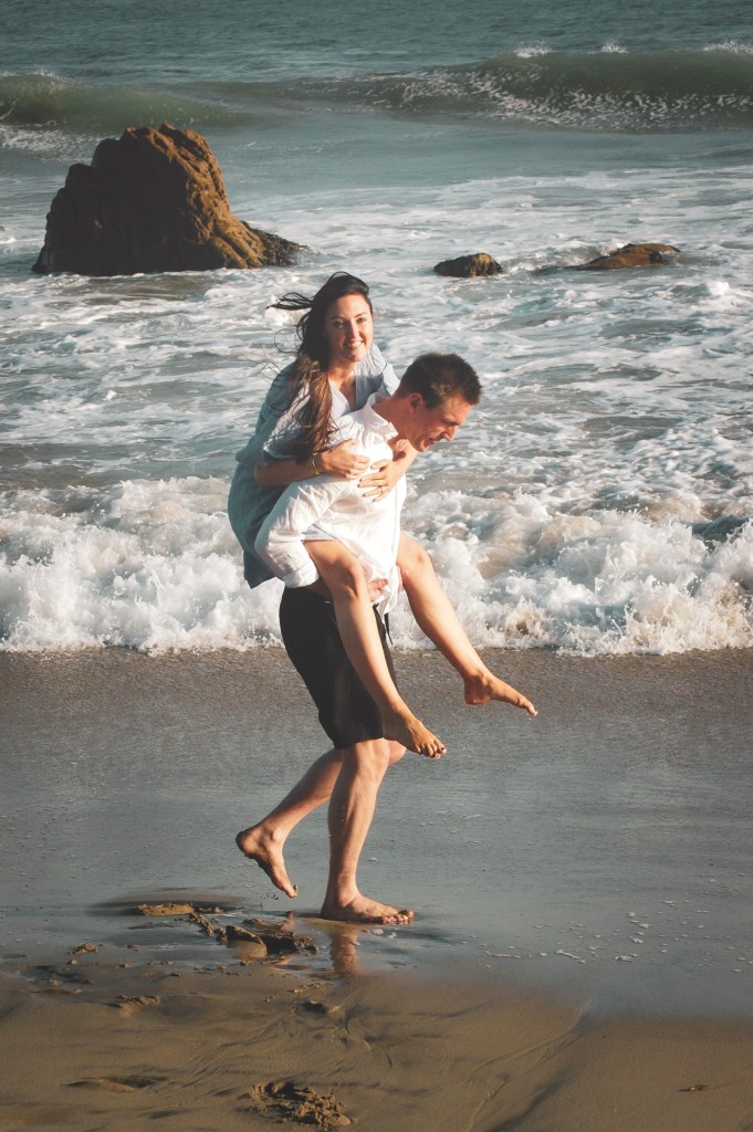 Man with a woman on his back strolling on the beach