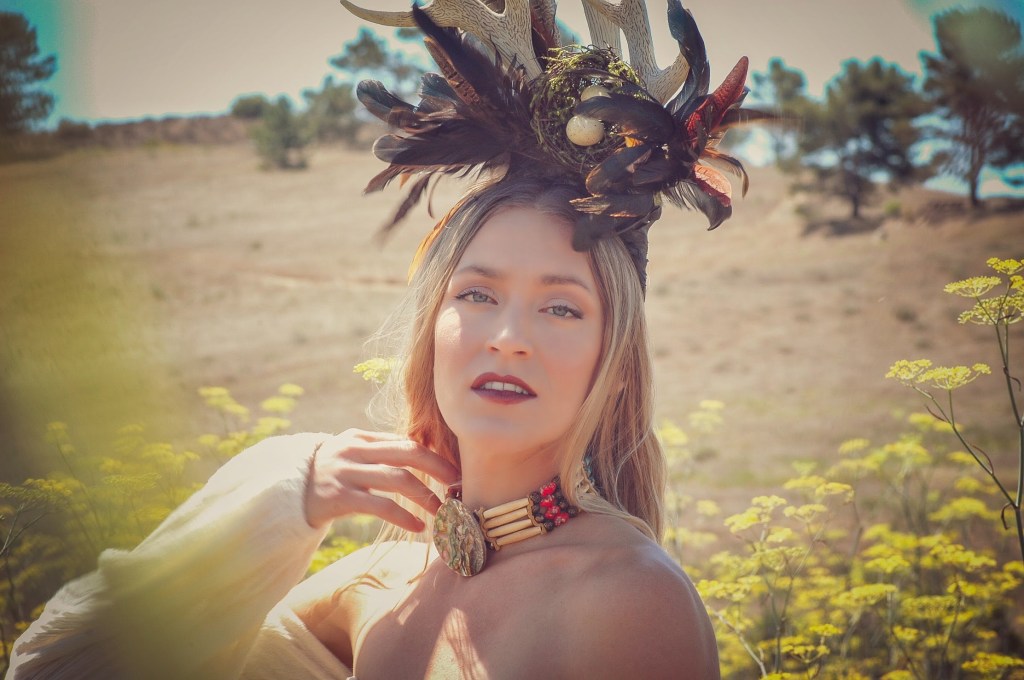 Woman in a mustard field wearing a horn head piece