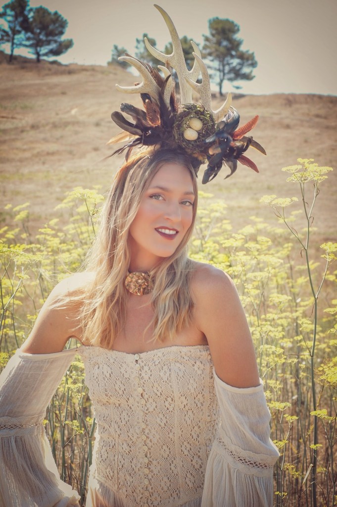 Woman in a mustard field wearing a horn head piece