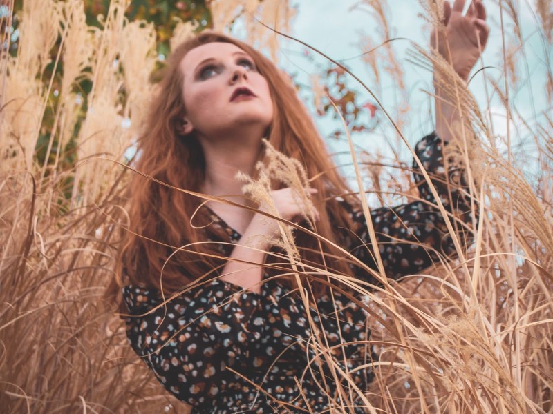 redhead Girl standing in pampas grass looking up into the sky